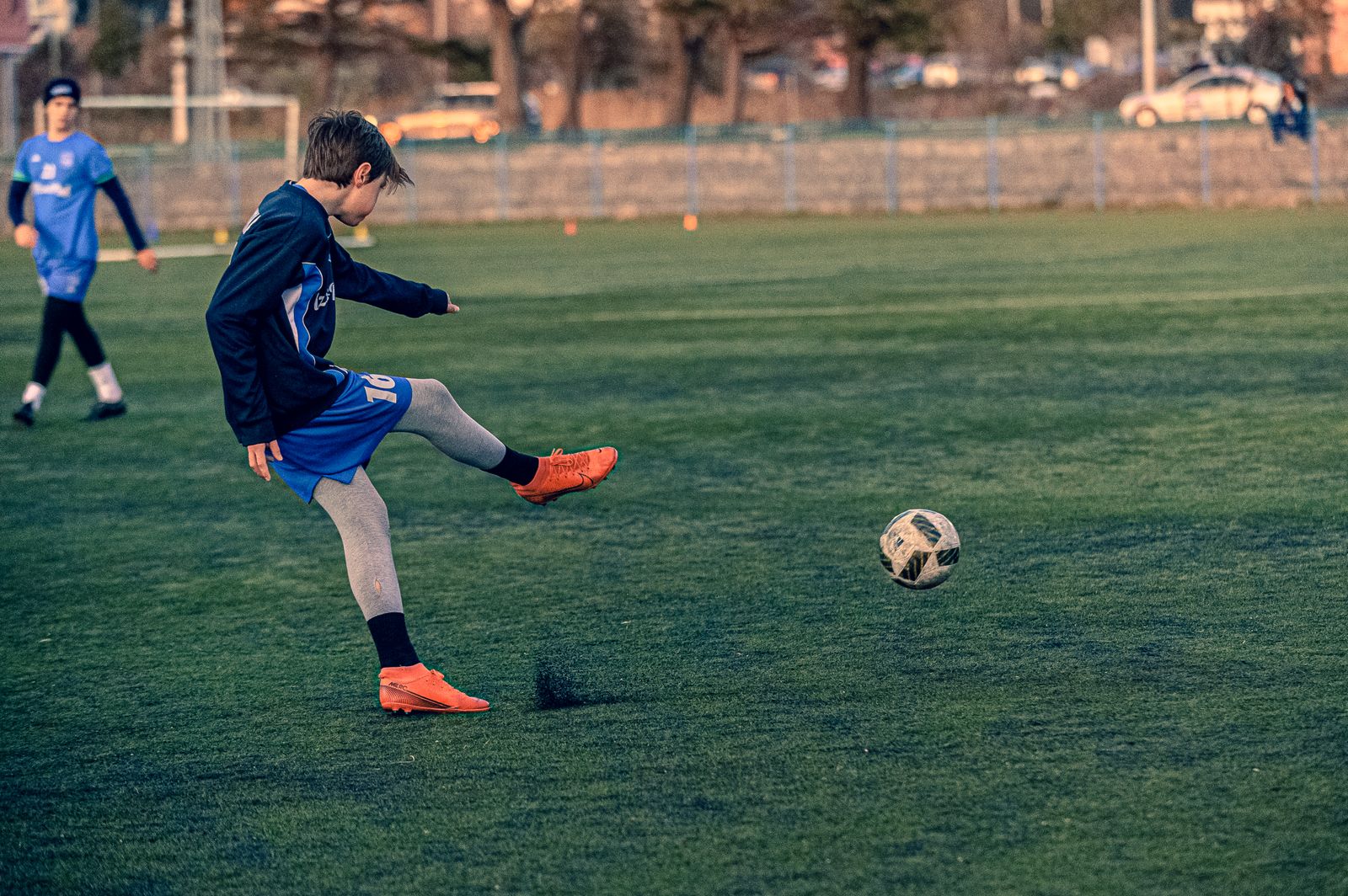 A young player striking the ball during an evening training session